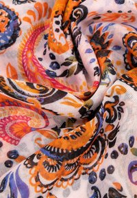 Tissu léger et coloré avec un motif floral en paisley dans des tons d'orange, de rose, de bleu et de noir sur un fond clair avec une texture douce.
