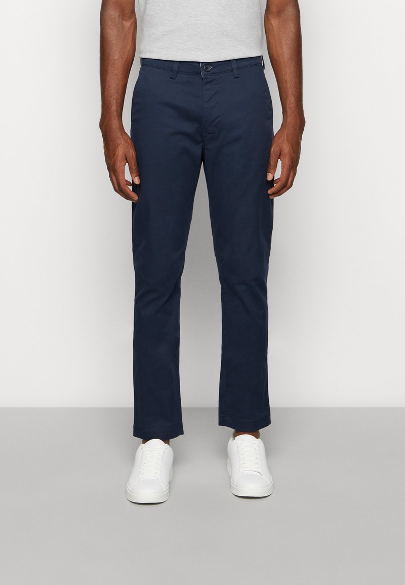 Chino blu navy realizzati in cotone, con design a gamba dritta, chiusura con bottone e due tasche frontali con una texture liscia.