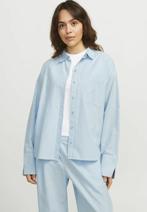 Camisa de rayas azul claro con un corte relajado, bolsillo frontal y diseño de botonadura, combinada con pantalones a juego en un patrón similar.