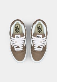 Braune Stoff-Sneaker mit weißen Schnürsenkeln, gepolstertem Innenraum, schwarzen Akzenten und einem Logo-Label auf der Zunge. Flache Gummisohle.