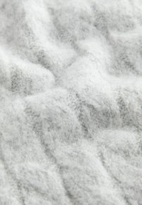 Tessuto grigio chiaro con una superficie morbida e texturizzata. Presenta un motivo ondulato e un aspetto fine e soffice. Adatto per abbigliamento o coperte.