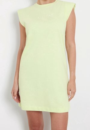 Robe courte jaune pastel sans manches avec épaulières et logo de marque brodé subtil sur la poitrine portée par une personne.