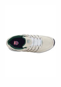 Sneaker beige con lacci bianchi, interno verde e dettagli neri. Presenta un logo sulla linguetta e una suola testurizzata.