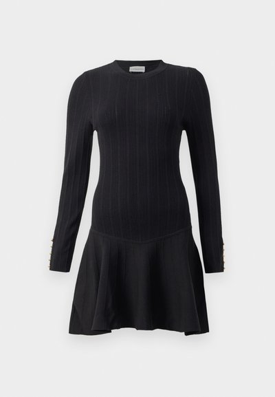 Abito a maglia nera a coste con maniche lunghe, corpo aderente e gonna a pieghe svasata. Presenta dettagli con bottoni dorati sui polsini delle maniche.
