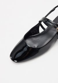 Scarpa slingback in vernice nera con punta quadrata, cinturini sottili e design minimalista. Texture liscia e finitura lucida.