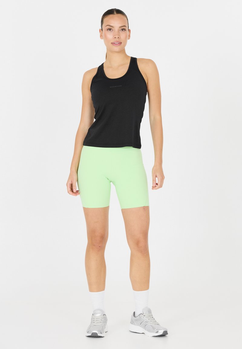 Musta ilmanhihainen tank top yhdistetty neonvihreisiin polkupyöräshortseihin. Ominaisuuksiin kuuluu sileä rakenne, urheilullinen istuvuus ja minimalistinen muotoilu.