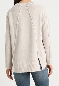Maglione di maglia beige chiaro con finitura testurizzata, caratterizzato da una vestibilità rilassata, fessure laterali e polsini e orlo a coste.