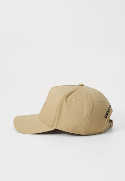 Casquette de baseball beige en tissu uni, avec une visière incurvée et une sangle ajustable. Présente un texte noir sur le côté et des œillets de ventilation.