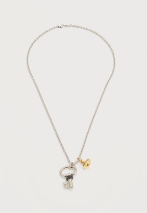 Silver chain necklace with key-shaped pendant and small gold round charm on white background.