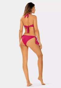 Zestaw bikini w kolorze fuksji z górą na halsie z zapięciem na sz nurkowym i dolnym, niskim poziomie z bocznymi wiązaniami, wykonany z gładkiego, elastycznego materiału.