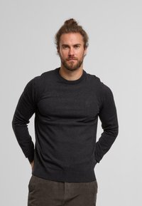 Pull gris foncé avec des manches longues, col et ourlet côtelés, fabriqué à partir d'un matériau doux. Design simple, peu de détails sur la poitrine.