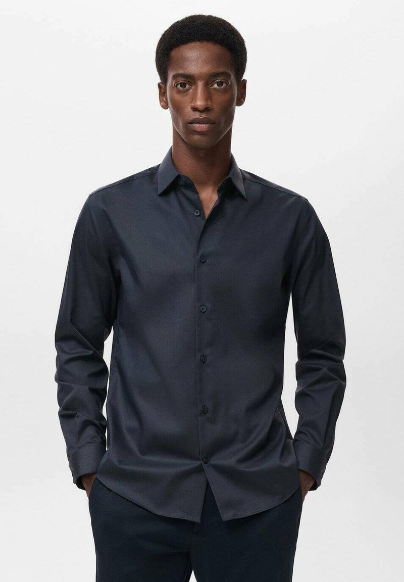 Temno modra srajca s kratkimi in dolgimi rokavi ter klasičnim ovratnikom. Ponaša se s slim fit krojem in usklajenimi gumbi.