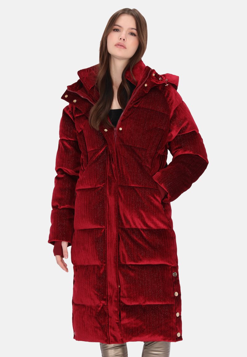 Piros kordbársony steppelt kabát magas gallérral, patentgombos részletekkel és nagy elülső zsebekkel. Puha tapintású, fényes felületű.