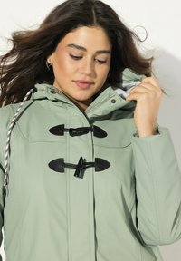 Mintgrön vattentålig jacka med huva, med svarta dragkedjeknoppar, dragkedjestängning och en mjuk grå foder.