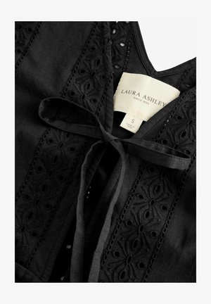 Fekete pamut blúz, amely hímzett díszítéssel rendelkezik elöl, hullámos szélekkel és megkötős, nyakba záródó fazonnal.