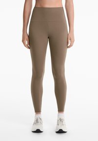 Magas derekú, olíva zöld leggings sima, rugalmas anyagból. Zökkenőmentes designt és testhezálló fazont kínálnak.