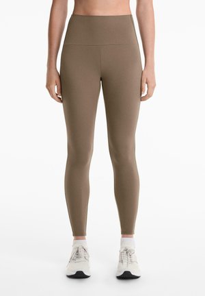 Leggings verzi măslinii, cu talie înaltă, realizate dintr-un material neted și elastic. Acestea au un design fără cusături și o siluetă ajustată.