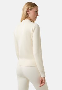 Cream-colored knitted sweater with a round neck, long sleeves, and ribbed cuffs. Designed with a smooth texture and fitted silhouette.