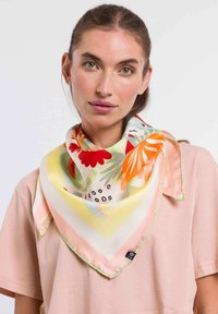 Pañuelo de seda, forma triangular, presenta vibrantes patrones florales en rojo, naranja y verde sobre un fondo amarillo pálido con un borde verde.