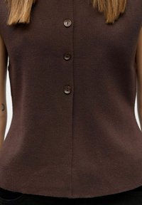 Haut sans manches marron en tissu tricoté, doté d'une fermeture à boutons sur le devant avec quatre boutons ronds sombres et une texture subtile.