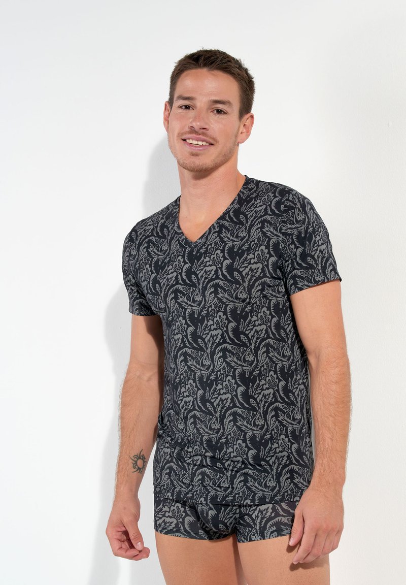 Black v-neck t-shirt with a floral pattern in gray, fitted design, soft fabric, worn with matching shorts. Smooth texture, casual style.