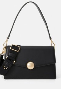 Črna usnjena torbica s strukturiranim dizajnom, z zlatim gumbom za zapiranje in snemljivim trakom iz blaga. Gladek tekstura in minimalni poudarki.