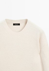 Maglione a coste beige con scollatura rotonda, con etichetta del marchio nera cucita all'interno del collo.