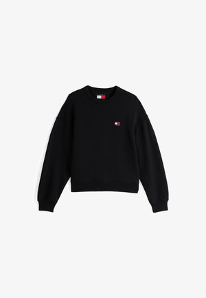 Sweatshirt noir avec un col ras du cou et des manches longues. Présente un petit logo en patch rouge, blanc et bleu sur la poitrine gauche. Tissu doux.