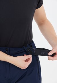 Marina blå utomhusbyxor med ett avtagbart bälte. Funktioner inkluderar en dragkedjeficka och justerbar midja med velcro- och spänneslutning.