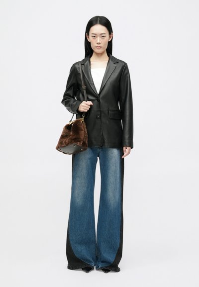 Must mustrakk, valge topp, üleväärde sinised denimipüksid küljepaneeliga ja pruun kunstkarv kott kuldse riistvaraga.