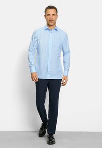 Camicia a maniche lunghe a righe azzurro chiaro in cotone con colletto button-down, abbinata a pantaloni blu navy e scarpe eleganti nere.
