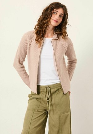 Light pink cardigan with ribbed texture, zip closure, and cable-knit accents; paired with loose green trousers. Simple, casual design.