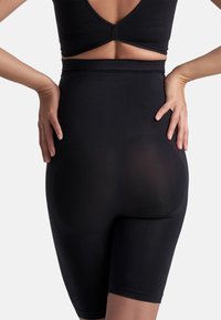 Pantalones cortos negros de tiro alto con una textura suave y longitud a mitad del muslo, que presentan un diseño sin costuras y un sutil efecto de modelado.