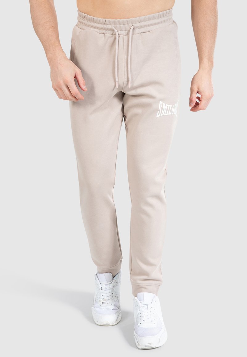 Beige joggerbukser med snoretræk i taljen, sidelommer og hvidt logoaccent. Fremstillet af blødt stof med et tapered leg-design.