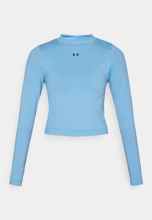 Lichtblauw cropped langemouwen top van glad stof, met een hoge hals en een klein logo in marineblauw op de borst.
