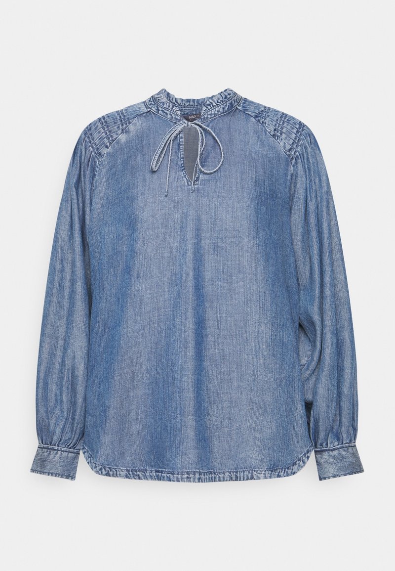 Blouse en denim bleu délavé à manches longues avec col et épaules froncés, encolure en forme de trou de serrure et fermeture à cordon à nouer au niveau du cou.
