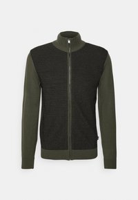 Vetoketjullinen neulepusero tummanvihreänä ja mustana. Siinä on korkea kaulus, teksturoitu neulottu etuosa ja sileät hihat. Valmistettu pehmeästä kankaasta.