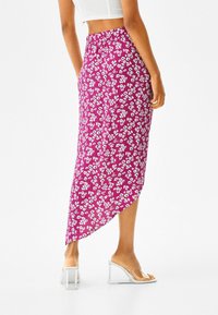 Lila blommig midikjol med hög-låg fåll, elastisk midja och lätt tyg som har små vita blommor. Klara klacksandaler.