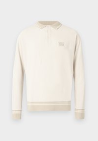 Ilgas rankovėmis smėlio spalvos polo marškinėliai su tekstūruotu megztu raštu, apykakle su sagomis ir juostelėmis apačioje bei rankogaliuose. Pasižymi subtiliu prekės ženklo ženklinimu krūtinės srityje.