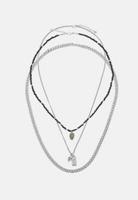 Trei coliere suprapuse: lanț argintiu, colier negru cu mărgele și pandantiv verde în formă de lacrimă, și lanț subțire argintiu cu pandantive dreptunghiulare și mici cu pete.