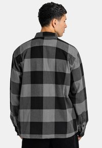 Schwarzes und graues kariertes Hemd mit Button-Down-Kragen, langen Ärmeln und einem lässigen Schnitt mit Zwei-Knopf-Manschetten. Strukturierter Baumwollstoff.