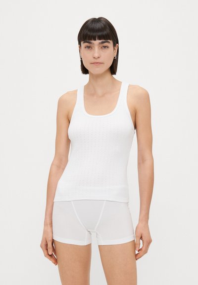 Débardeur blanc à encolure carrée et texture côtelée, associé à un short boxeur blanc sans coutures, tous deux avec une finition lisse.
