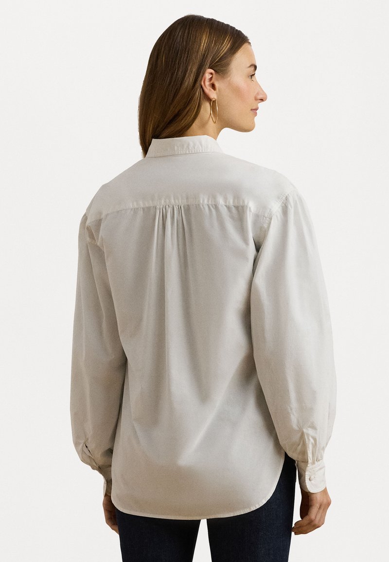 Jasnoszara koszula z długim rękawem, z kołnierzykiem zapinanym na guziki, zebrań w tylniej części i elastycznymi mankietami. Gładka tekstura i luźny krój.