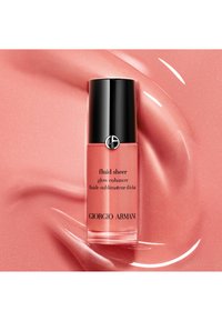 Bouteille en verre de Giorgio Armani Fluid Sheer dans une teinte rose avec un bouchon noir, arborant un texte en noir et un fini réfléchissant sur un fond rose scintillant.