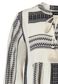 Kremsfärgad klänning i tyg med svarta geometriska broderade ränder, rund hals med framsidan tasselknut och långa ärmar med mönstrad detalj.