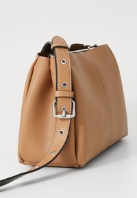 Brown leather handbag with a textured finish, featuring a removable strap and silver hardware. The design is structured with a flat base.