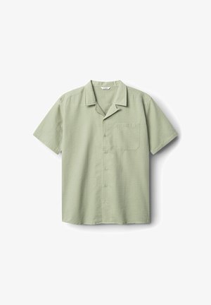 Lühikese varrukaga helesinine särk, millel on tekstureeritud kangas, nööbiv lähenemine ja üks tasku vasakul rinnal.