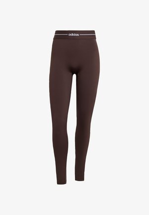 Brown leggings made of stretchy fabric with an elastic waistband featuring a white Adidas logo. Fitted design, smooth texture, full-length.