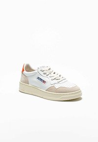 Sneaker bianco con punta forata, dettagli in suede beige, linguetta arancione sul tallone e suola in gomma. Branding visibile sul lato.