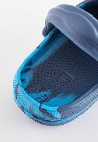 Kék és sötétkék slip-on szandál, amely texturált gumiból készült, mintás pánttal és lélegző perforációkkal az talpbetéten és az oldalain.